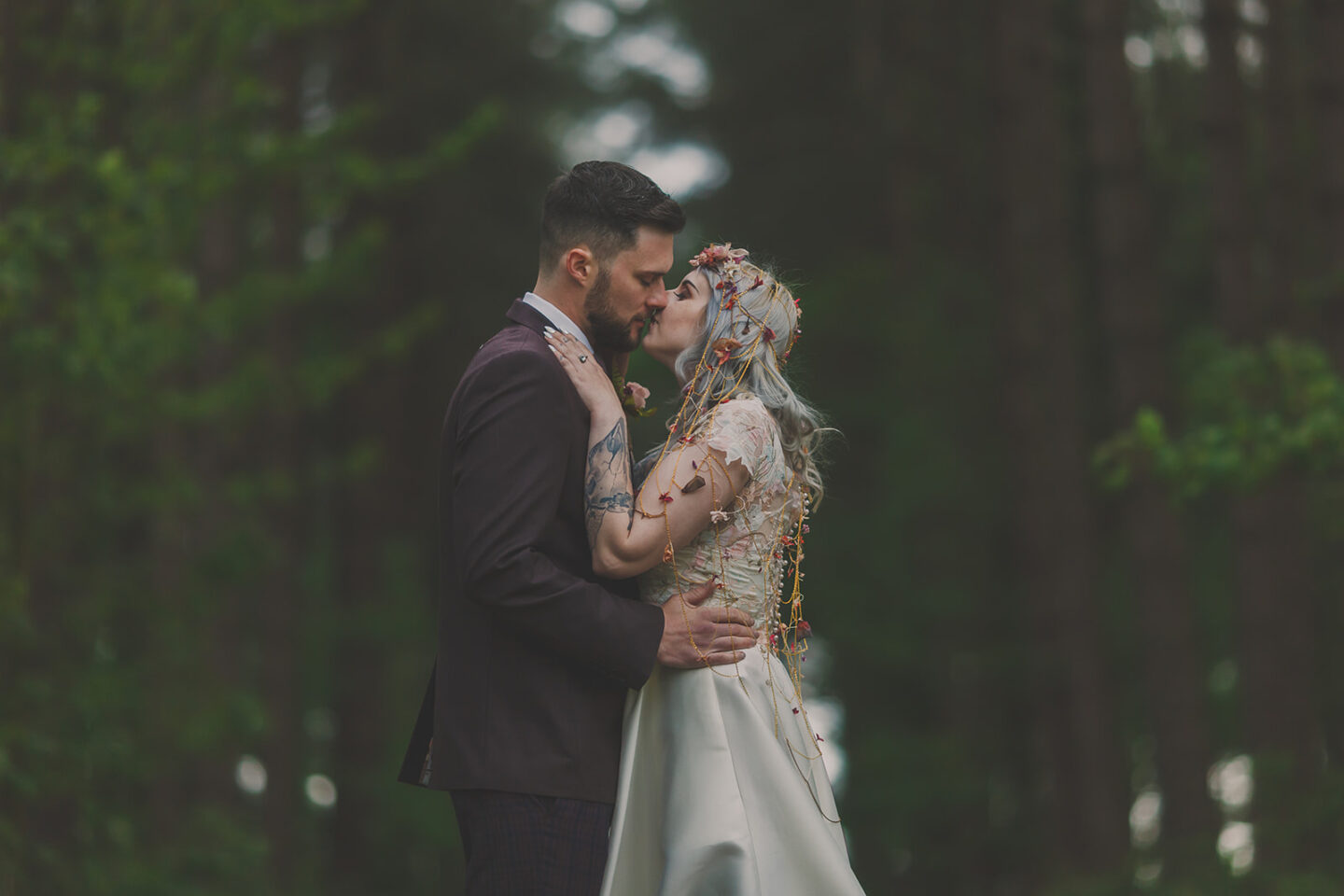 Bride and groom kiss in woodland setting